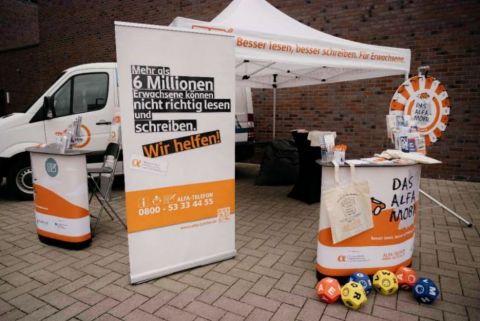 Das ALFA-Mobil Team informiert am Infostand interessierte Bürgerinnen und Bürger sowie ganz konkret Menschen mit Lese- und Schreibschwierigkeiten.